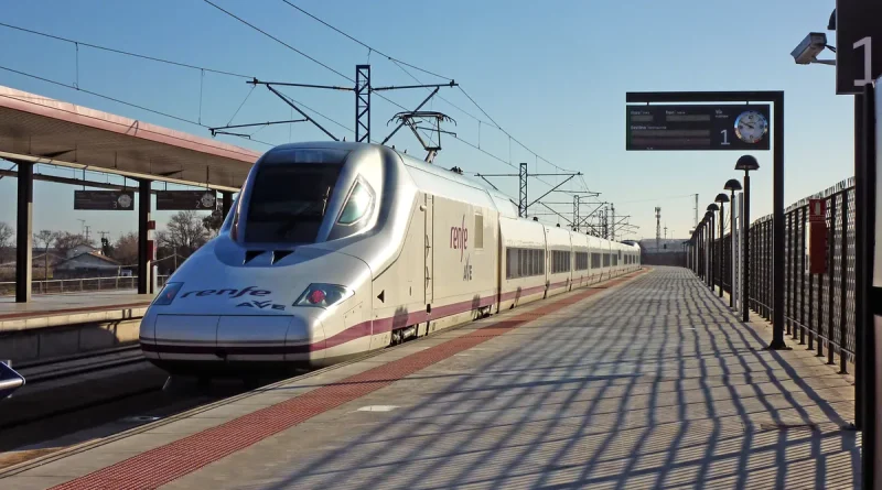A white Renfe AVE high-speed train waiting at a station platform in Toledo