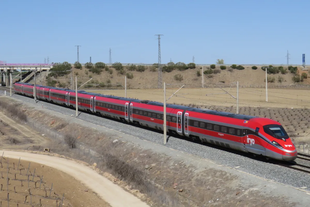 A red Iryo high-speed train travelling through dry countryside in Spain