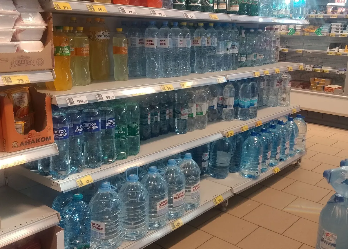 Supermarket shelves stocked with large bottles of drinking water