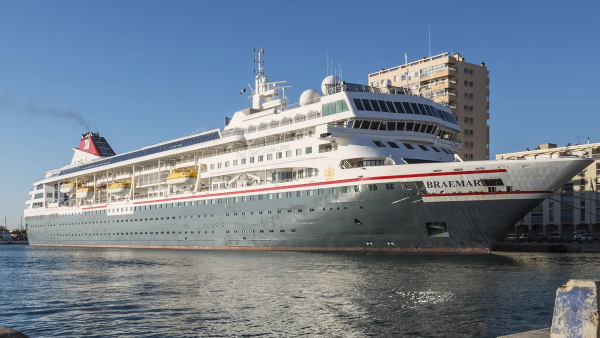 A white cruise ship moored in a harbour beside a quay